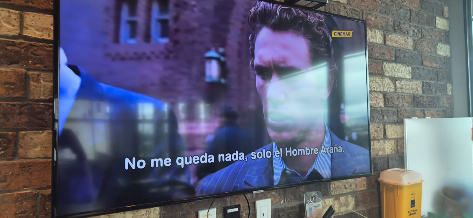 A television in an office common area showing a scene from a Spider-Man movie.