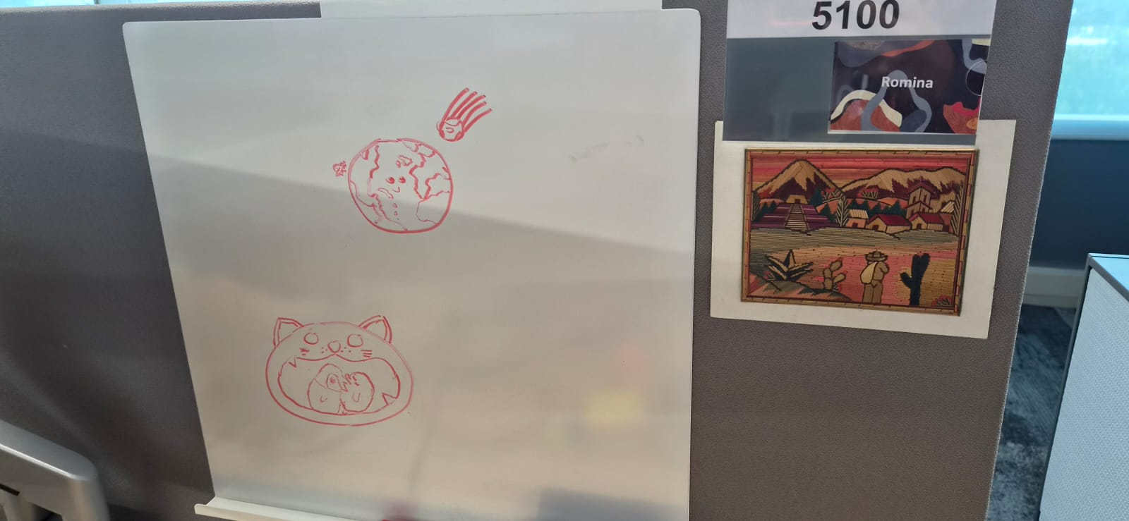 A workspace divider decorated with red line-art illustrations and a framed landscape print.